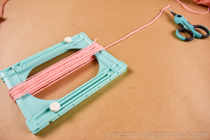 plastic tassel maker wrapped around several times with pink yarn