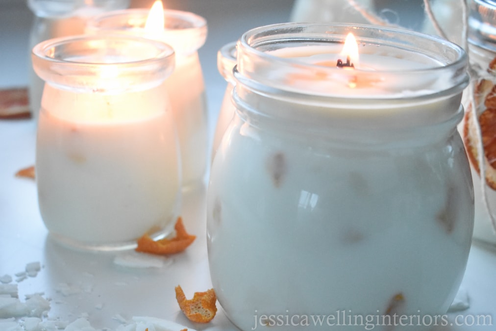 how to make soy candles: 2 white soy candles burning, with orange peel