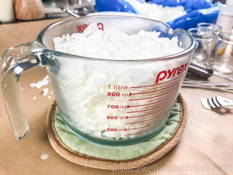 close-up of glass measuring cup filled with natural soy wax flakes, ready to be melted in the microwave