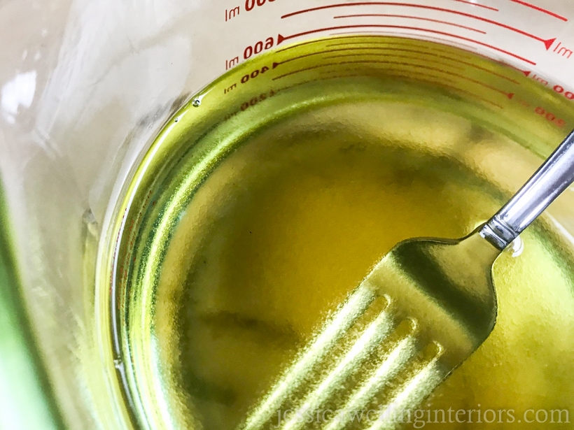 close-up of fragrance oil being stirred into melted soy wax with a fork