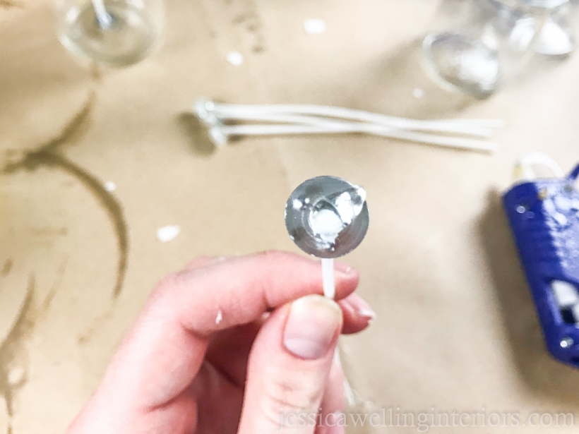 hand holding a candle with with a dot of hot glue on the bottom metal portion