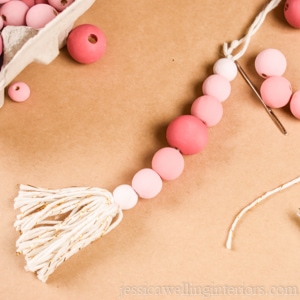 close-up of a pink wood bead Christmas ornament with a tassel on the end