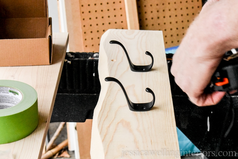 wooden coat rack with 2 black metal hooks sitting on top