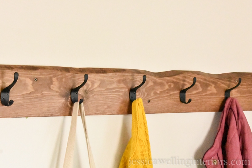 diy wall coat rack with a live edge and coats hanging from it