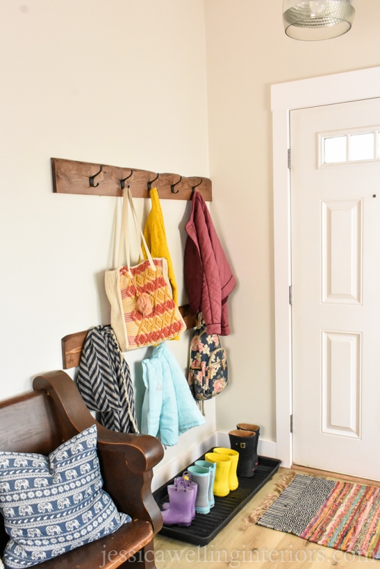 entryway with boot tray and rain boots lined up in it and live edge wood coat racks above it