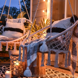 2 macrame swings on a front porch with a black and white patterned outdoor rug