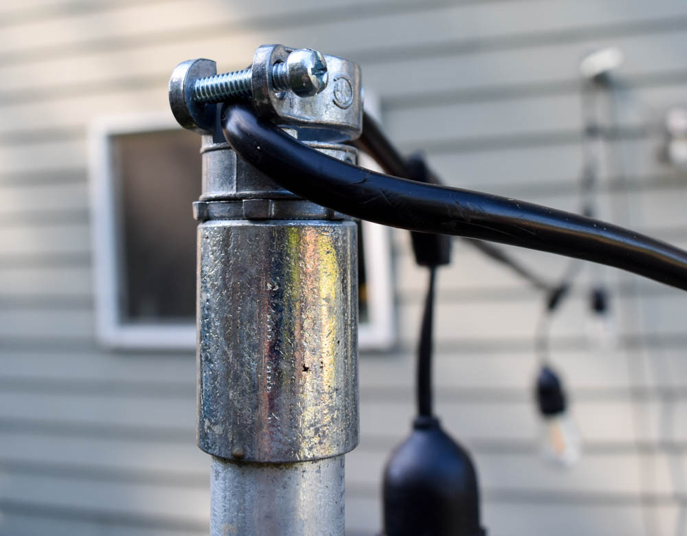 close-up of the top of a DIY string light pole with the light string threaded through