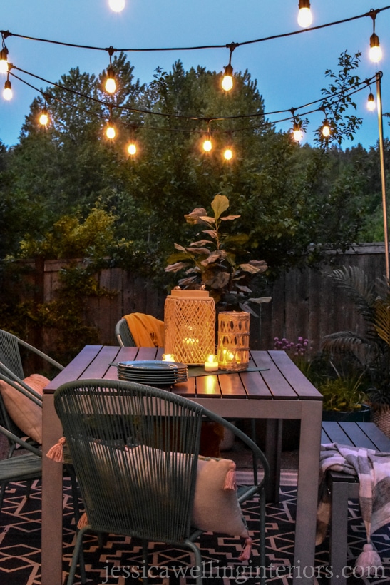 glowing patio lights hung from DIY conduit poles over an outdoor dining table