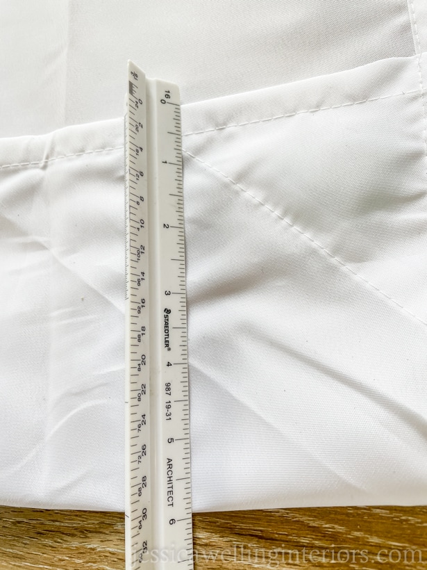 close-up of the hem of a DIY outdoor curtain panel with a ruler to measure the hem width