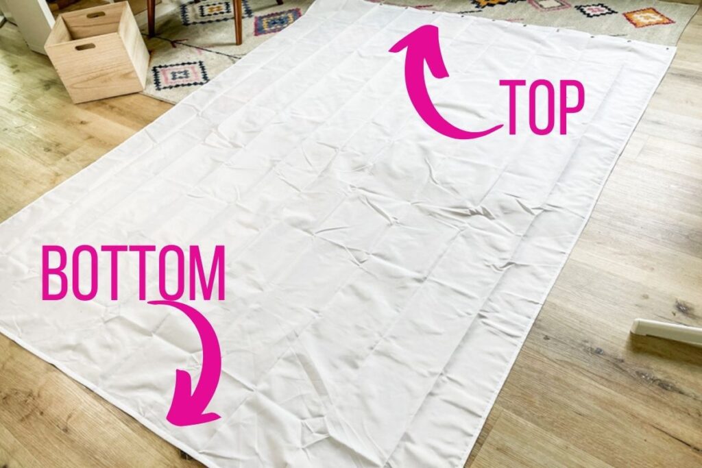 extra-long shower curtain laid out on the floor, ready to be made into an outoor curtain for the gazebo