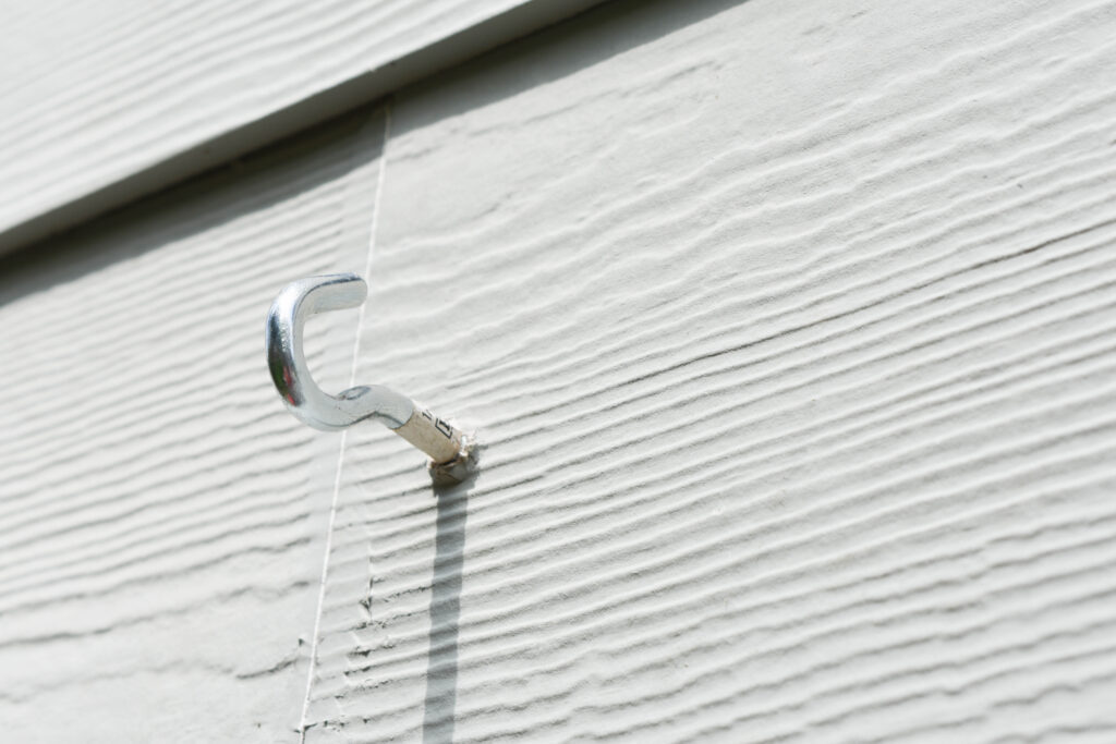 close-up of a cup hook in the siding of a house to hang string lights