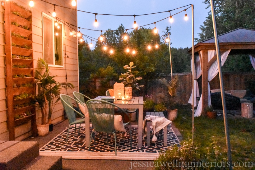 backyard patio lit with glowing string lights hung from DIY string light poles