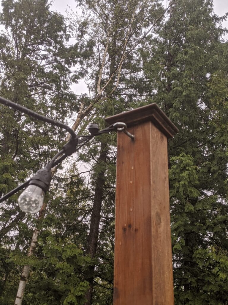 close-up of string light post on deck railing showing an eye hook