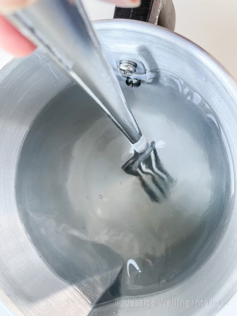 close-up of a pitcher of melted wax being stirred with a fork