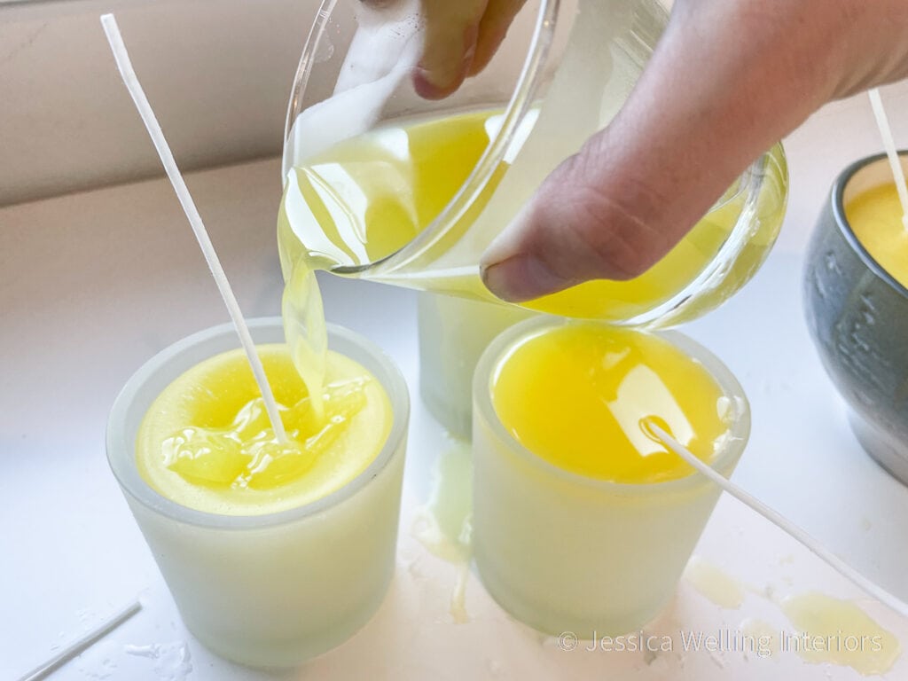 close up of hand pouring paraffin into a candle holder to make a DIY citronella candle