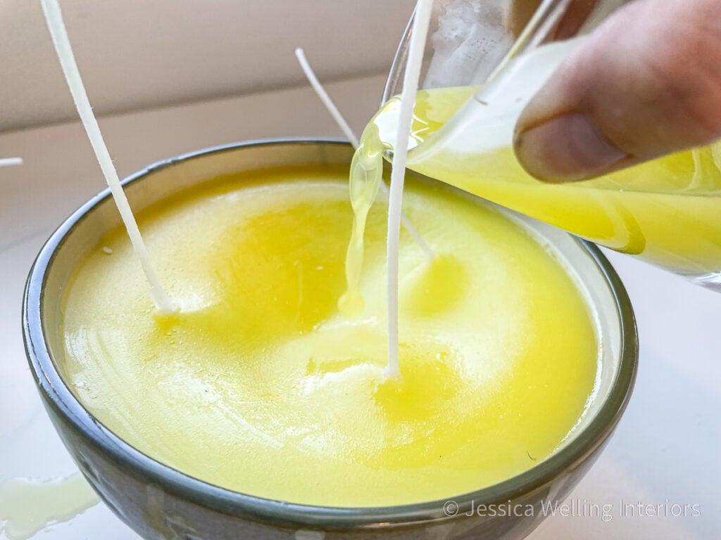 hot wax being poured to cover the top of a large citronella candle