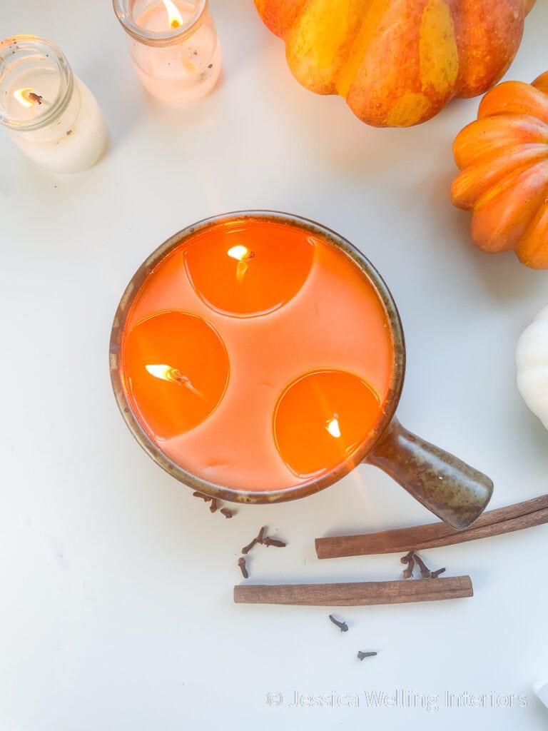 overhead view of orange Fall-scented paraffin candle with pumpkins, cinnamon sticks, and cloves