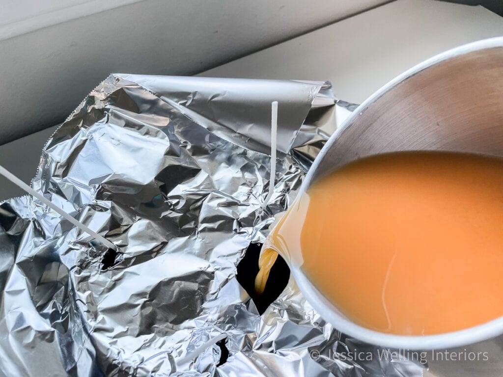 orange candle wax being poured into a ceramic bowl to make a DIY candle