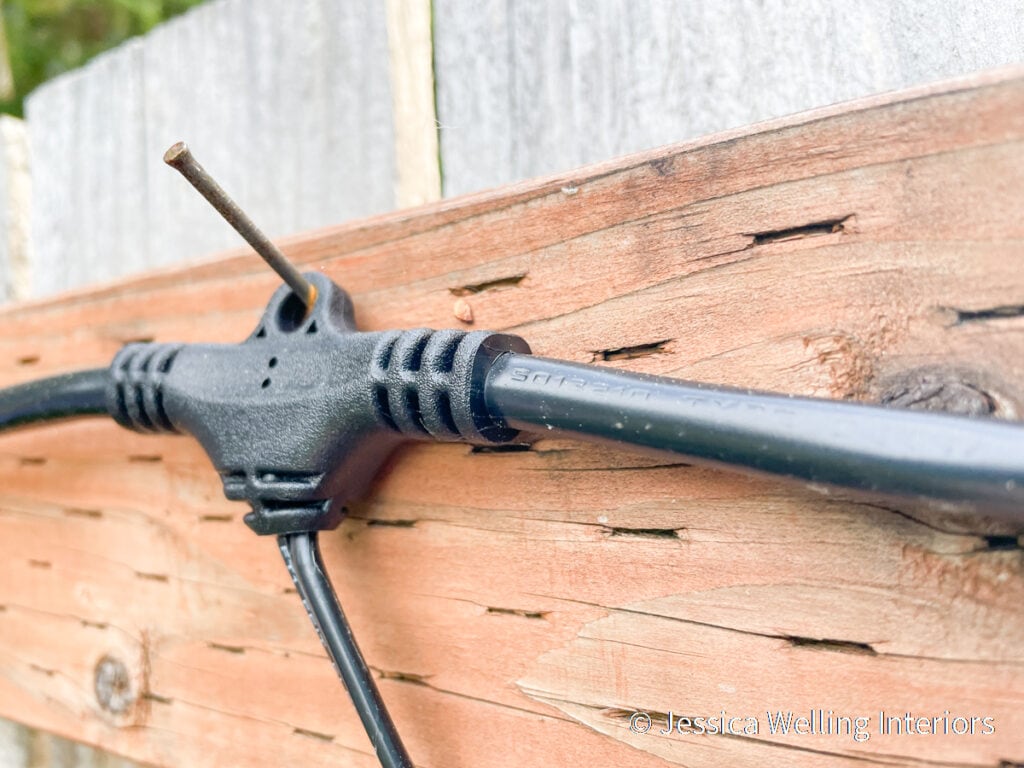 close-up of a finish nail holding string lights on a fence