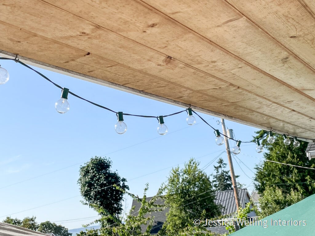 string lights attached to the underside of a deck roof with cup hooks