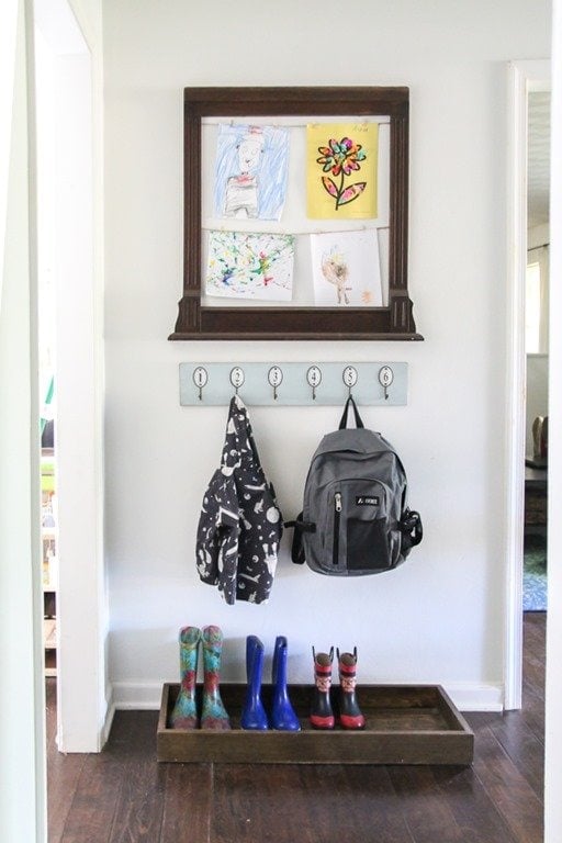 entryway with a DIY boot tray and wall mounted coat hooks, plus a kids art display frame