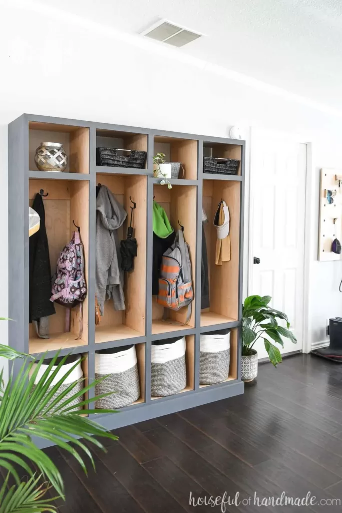 DIY mudroom cubbies next to the front door with baskets for shoe storage