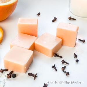 light orange soy wax melts with cloves and an orange in the background