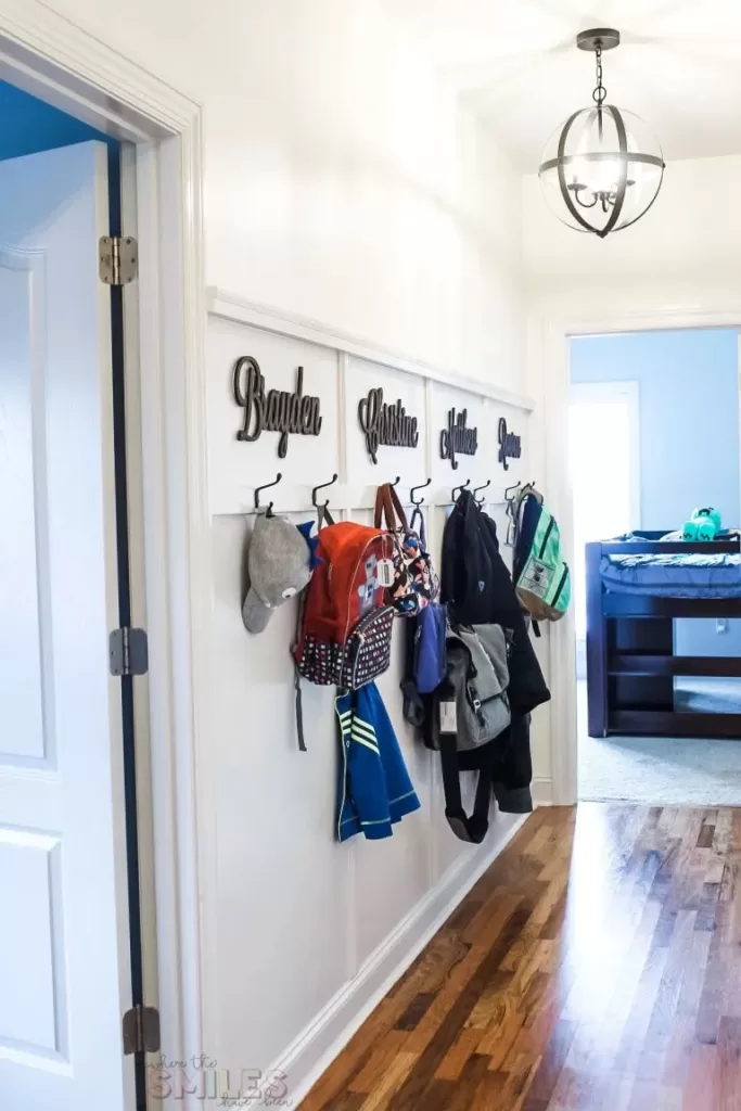 entryway with wall mounted coat hooks for each family member hunng with coats and backpacks
