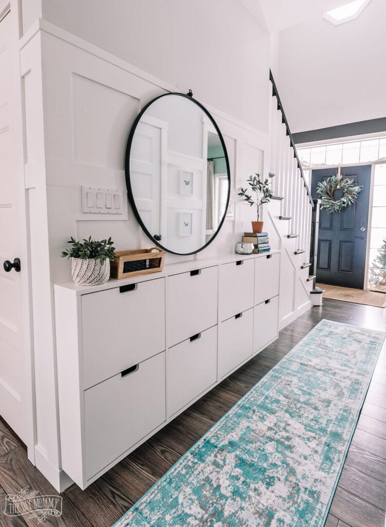 farmhouse style entryway with Ikea shoe cabinets and a round mirror