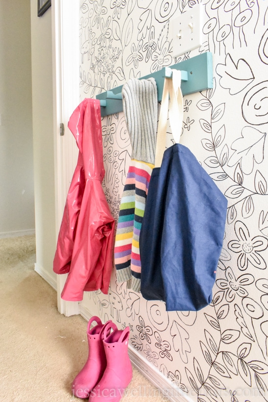 children's room with a wall-mounted coat rack holding jackets and sweaters