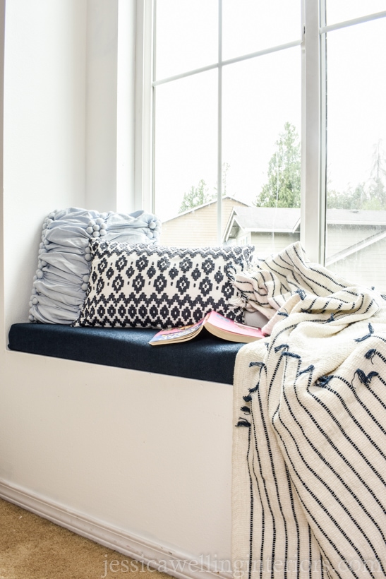 window seat with a DIY upholstered seat cushion, throw pillows, a blanket, and a book