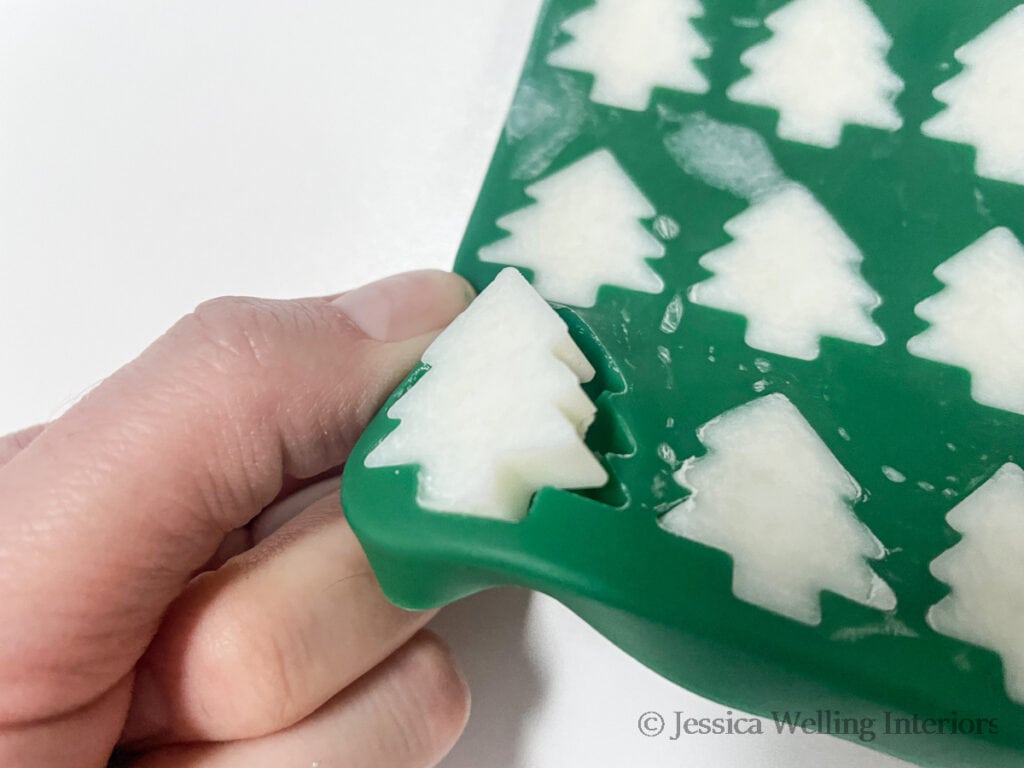 hand removing Christmas tree-shaped wax melts from a silicone mold