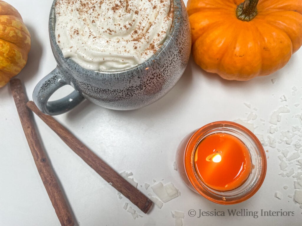 pumpkin spice-scented candle with a pumpkin spice latte and pumpkins