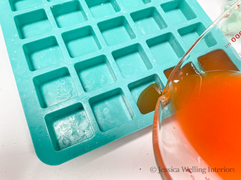 pumpkin spice-scented wax being poured into a wax melt mold