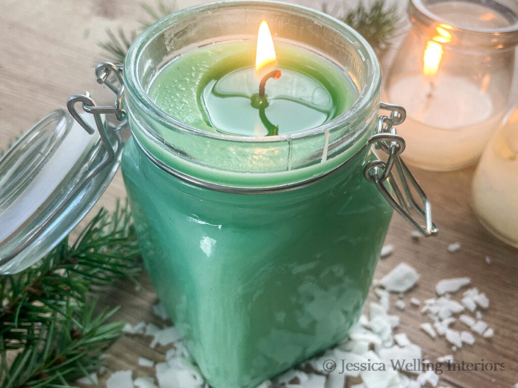 Juniper Spruce & Balsam Fir scented candle burning with fir boughs in the background