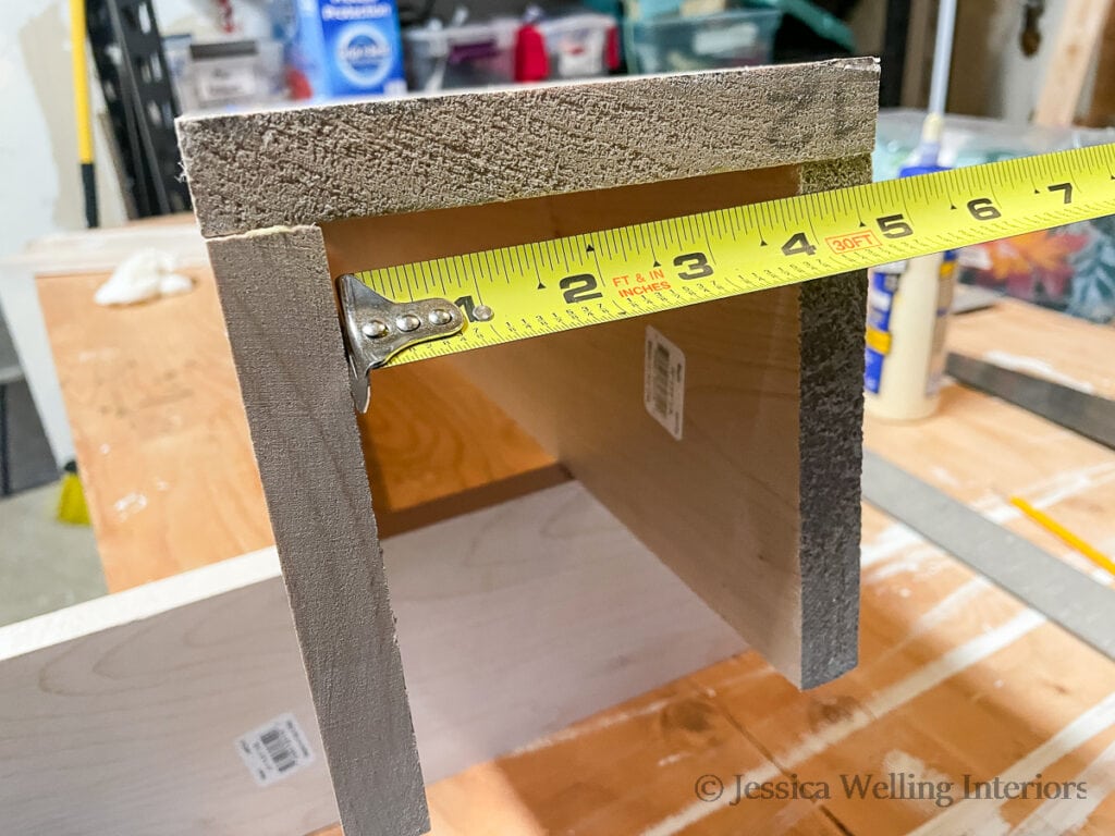 end of a partially assembled box beam mantel with a tape measure measuring the inside edge