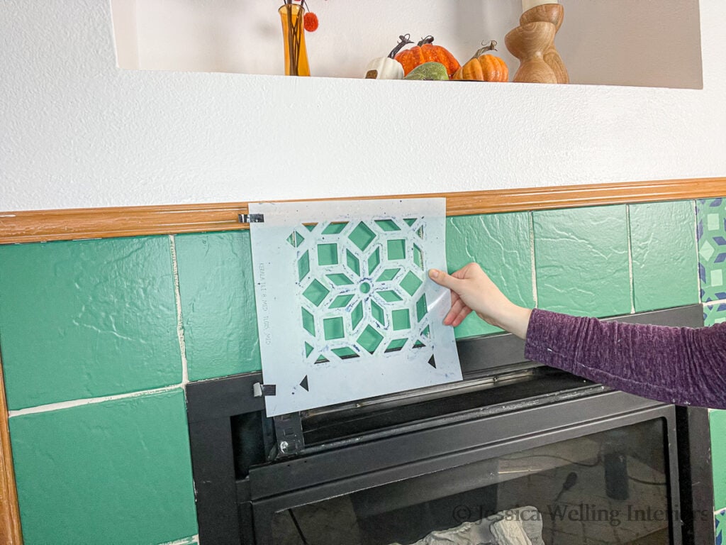 Moroccan tile stencil being taped to a fireplace tile.