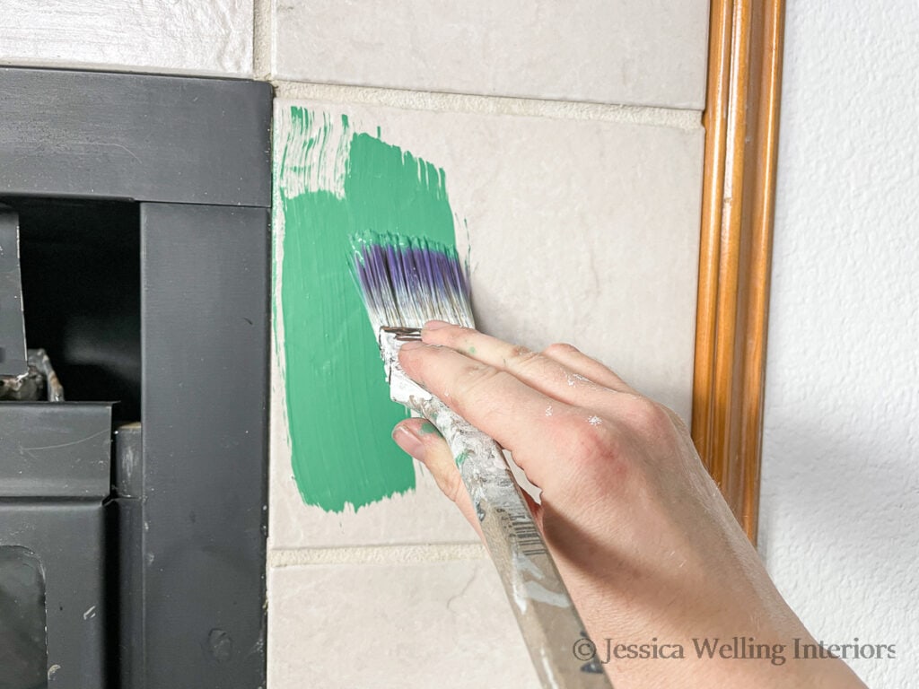 hand painting fireplace tile green with a paintbrush