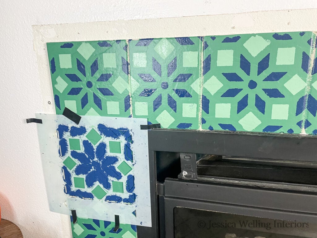 fireplace tile surround painted with a tile stencil and the stencil taped to one of the tiles
