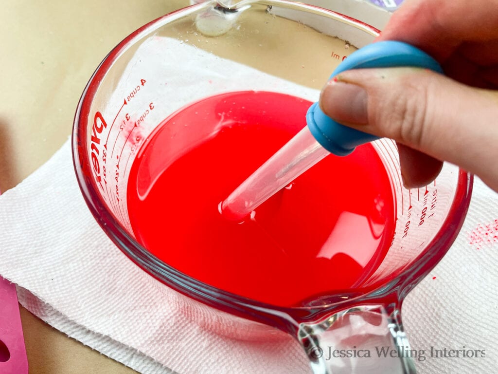 hand using an eye dropper to fill wax melt molds with hot soy wax