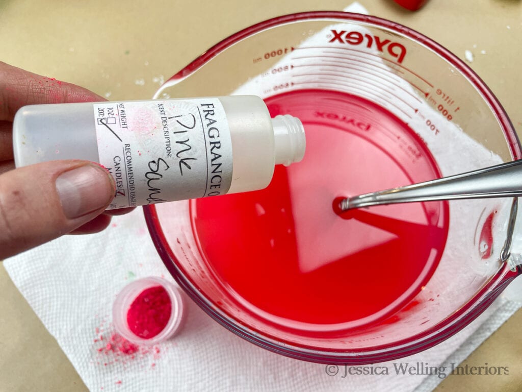 fragrance oil being poured into a bowl of hot wax