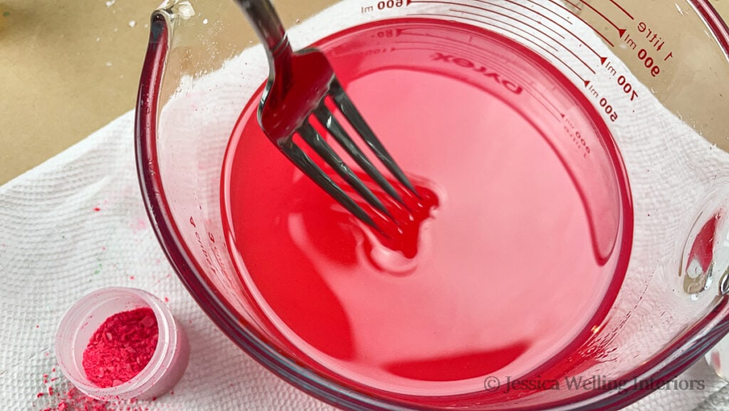 fork stirring a bowl of red melted soy wax