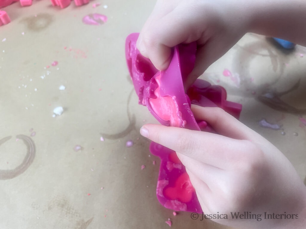 hands removing hardened soy wax melts from a silicone mold