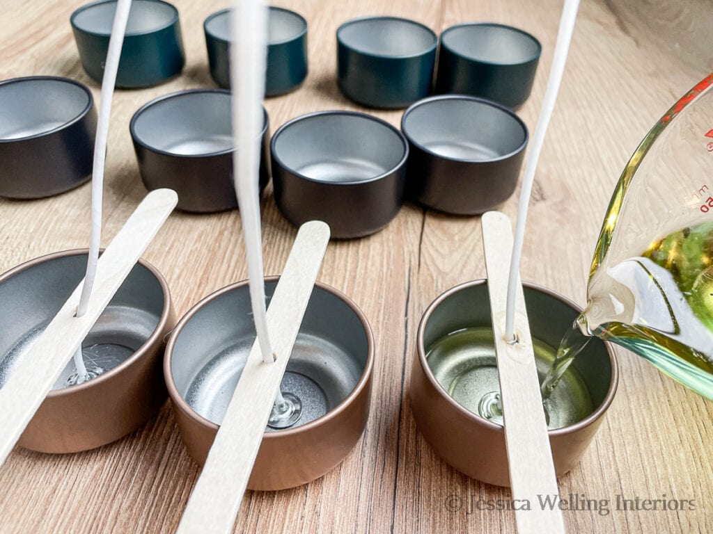 candle tins with wicks and wick holders in place, with hot wax being poured into them