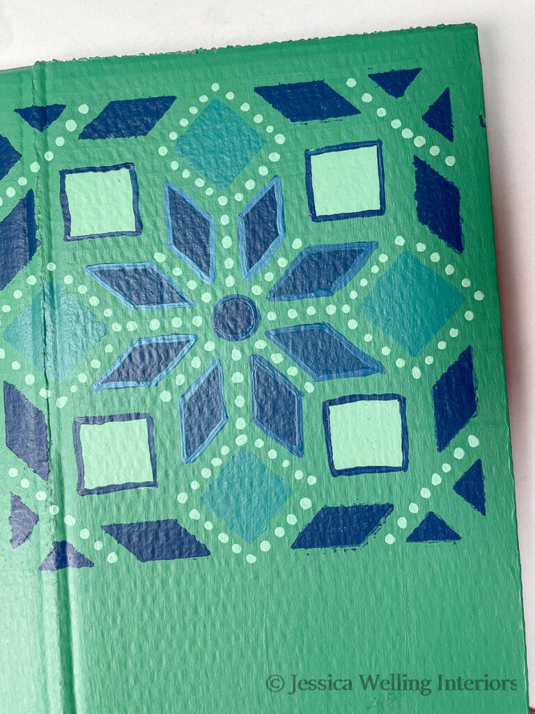 close up of cardboard with green Moroccan tile pattern stenciled on it