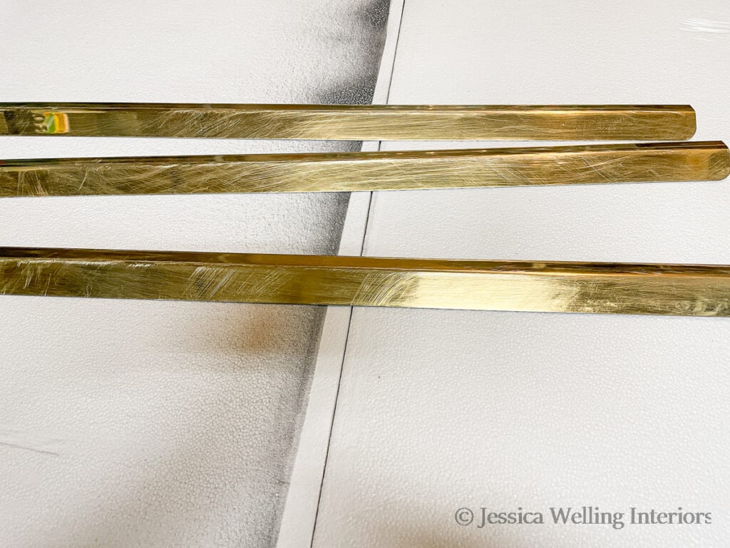close-up of brass-colored slats that have been removed from the top of the gas fireplace insert, sanded, cleaned, and ready to be painted with fireplace spray paint