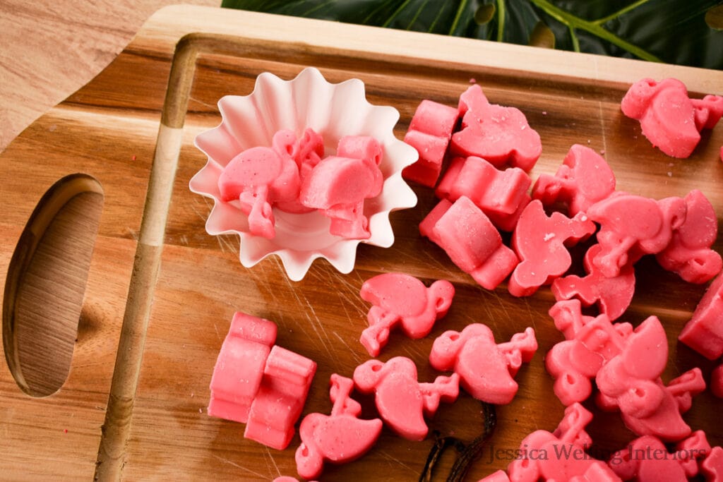 wood cutting board covered in bright pink flamingo-shaped wax melts made with Pink Sands fragrance oil