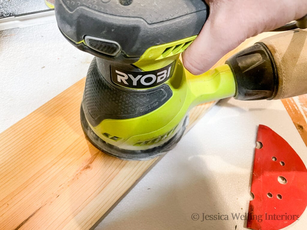 board being sanded with an orbital sander to make DIY floating shelves