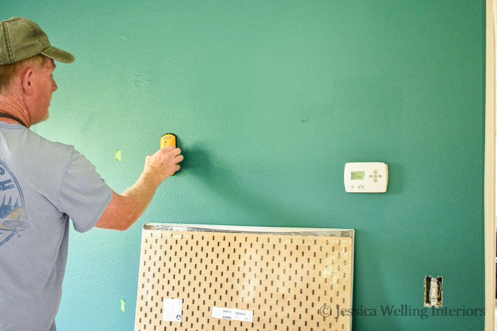 man using a stud finder to locate studs in a wall
