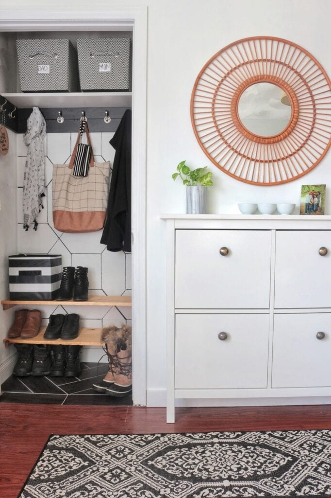 entryway coat closet with shelving for shoes and hooks and a shoe cabinet in the foreground